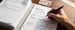 Personne remplissant un formulaire administratif sur un bureau en bois