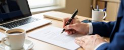Personne signant une lettre de démission sur un bureau professionnel