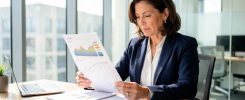 Une dirigeante analyse des relevés financiers et des graphiques de trésorerie dans un bureau moderne et lumineux.
